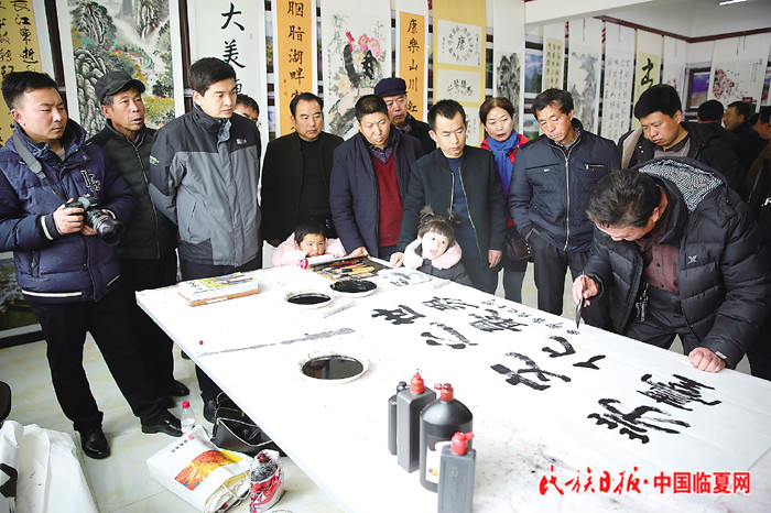 2月14日，康乐县举办“弘扬正能量 助推新康乐”书画摄影展。书法家现场挥毫泼墨,吸引群众驻足观看。（刘红红 黎元军）.jpg